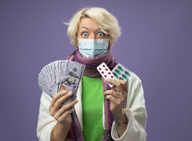 foto mostra uma senhora usando máscara facial e segurando em uma das mãos um maço de dinheiro e na outra cartelas de remédio, remete ao artigo Quando a inovação justifica a exploração: retrocessos e mentiras no desmonte da ética em pesquisa no Brasil 