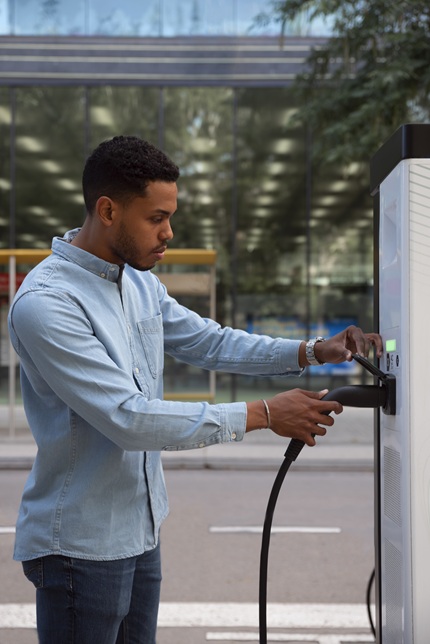 foto de jovem, homem, negro segurando um carregador de carro elétrico 