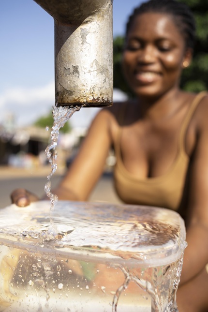 mulher jovem, negra pegando água na bica, remete a matéria O que funciona: soluções, escala e a corrida contra o colapso hídrico