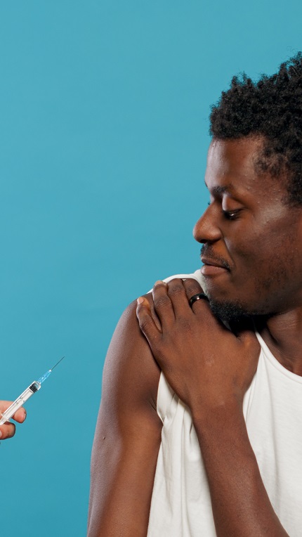 Foto mostra homem negro tomando vacina contra covid.