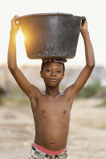 foto mostra criança negra carregando balde de água na cabeça, remete a matéria Condições climáticas extremas podem contribuir para crise hídrica nos próximos anos