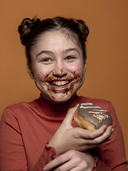 foto mostra menina branca com a bova lambuzada de chocolate