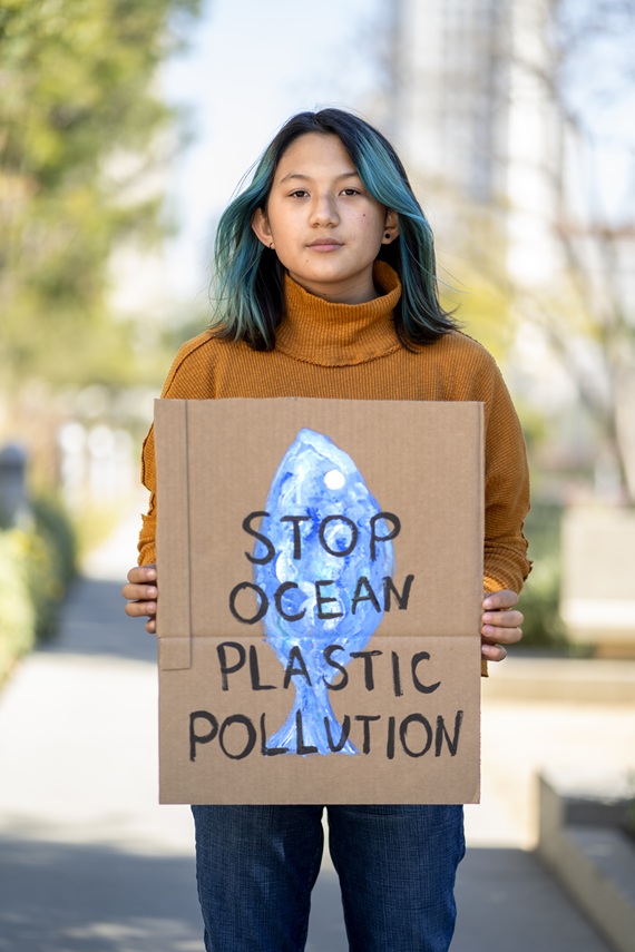 FOTO MOSTRA JOVEM ASI[ATICA SEGURANDO UM CARTAZ PEDINDO PARA PARAR A POLUIÇÃO NOS OCEANOS, REMETE AO LANÇAMENTO DO HOTSITE NEO OCEAN