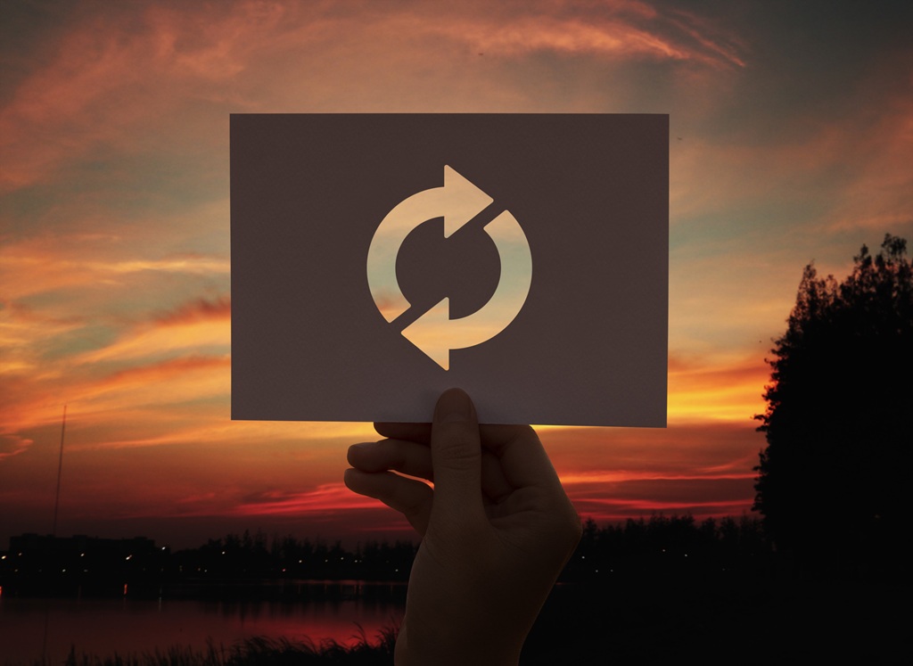 foto de uma mão segurando o símbolo da reciclagem com o por do sol ao fundo, remete a matéria Escassez da reciclagem no país: como a logística reversa pode mudar esse cenário